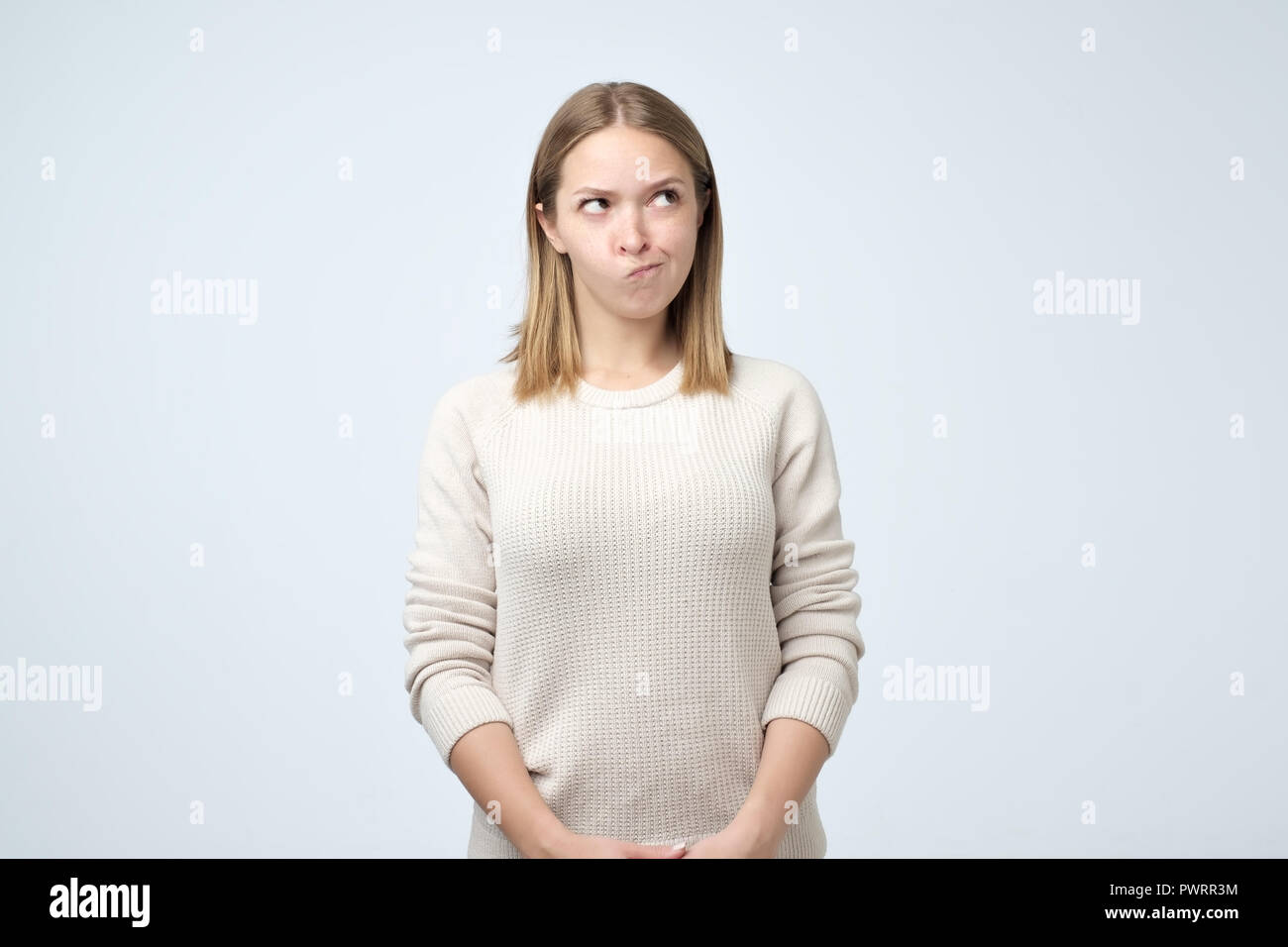 Grumpy young caucasian woman, having annoyed look and frowning, feeling ...