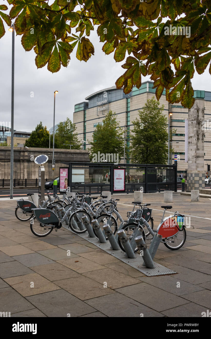 Belfast Bikes sponsored by Coca Cola Zero in Lanyon Place, Belfast. Public hire bikes for city centre transport. Bus stop and Laganside Courts in back Stock Photo
