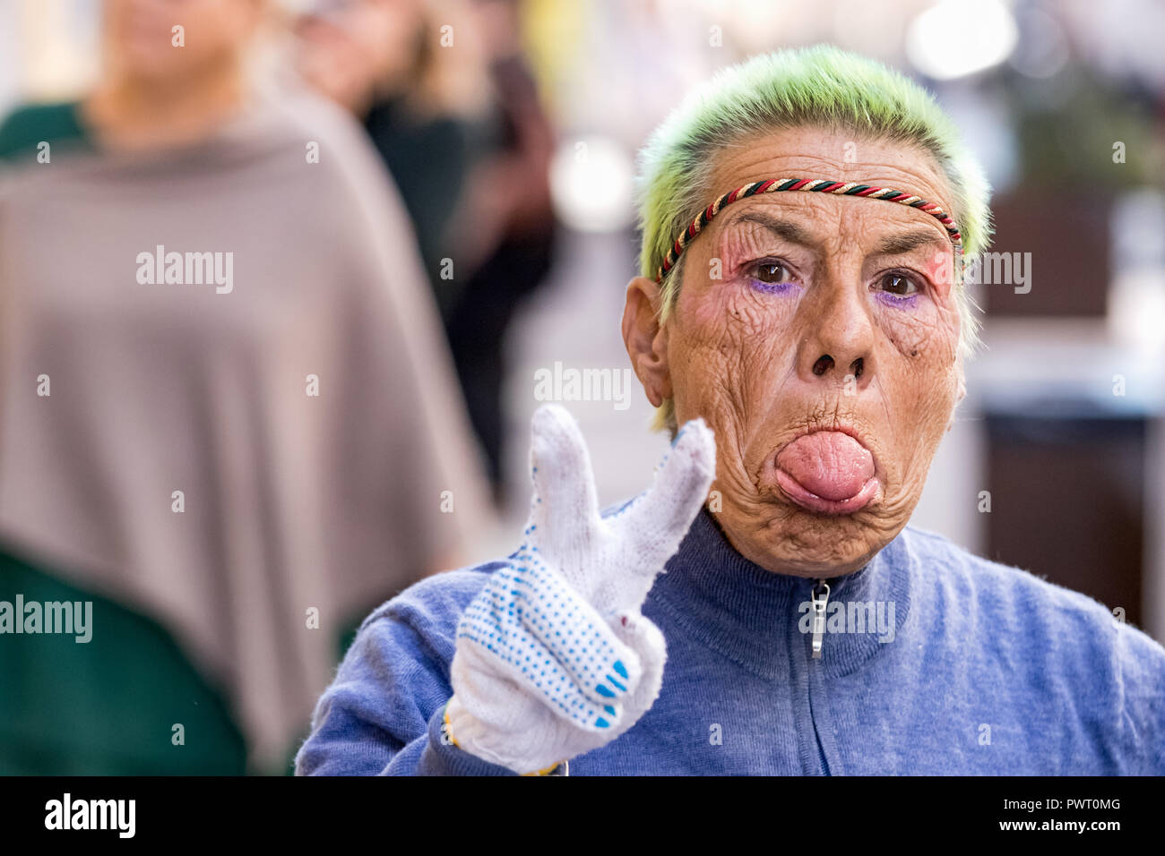 Ancona, Italy - September 27th, 2018: A funny senior woman taking out her tongue and making the victory sign with her fingers looking camera in the st Stock Photo