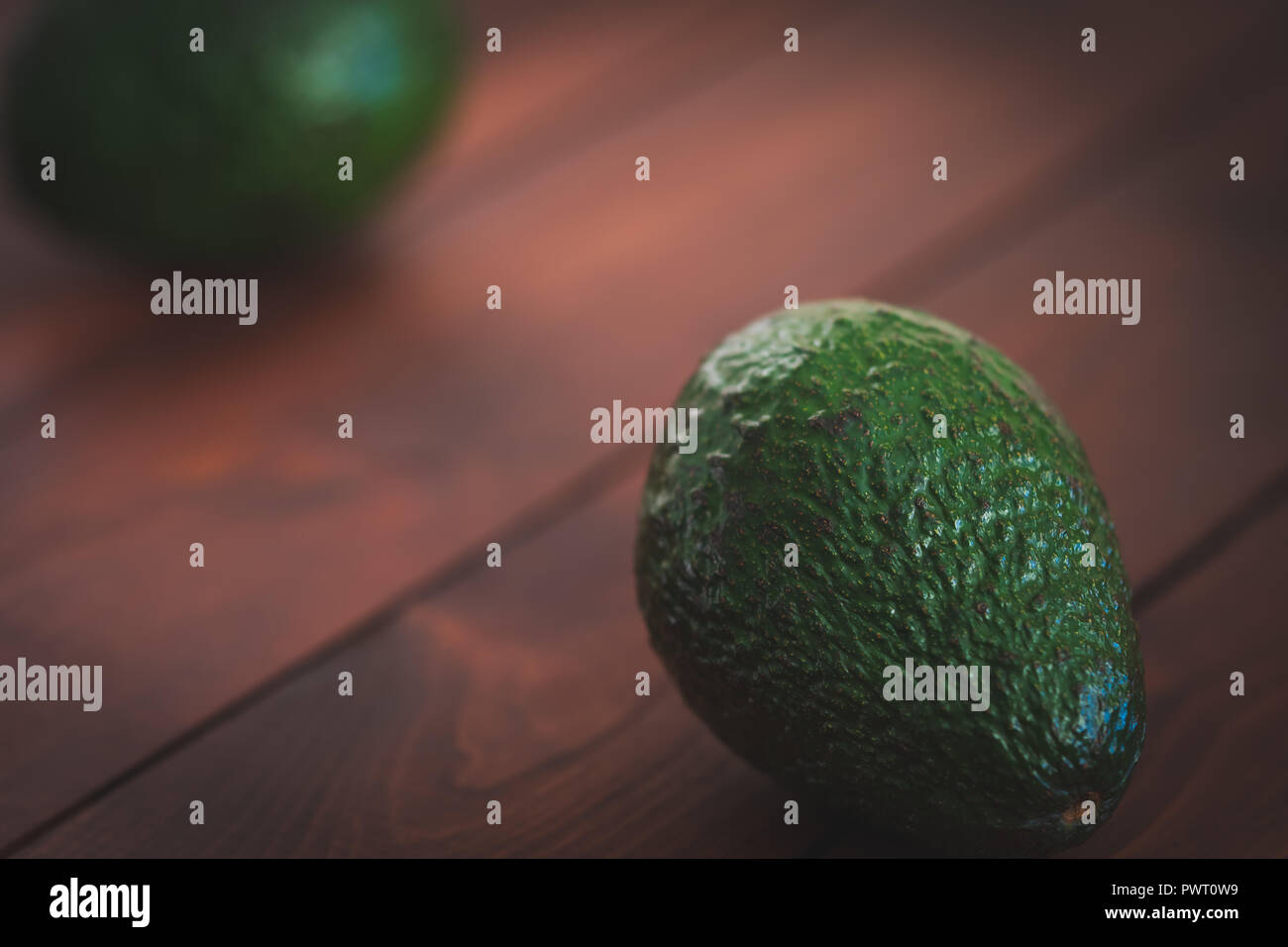 Two avocados on a brown cutting board. Stock Photo