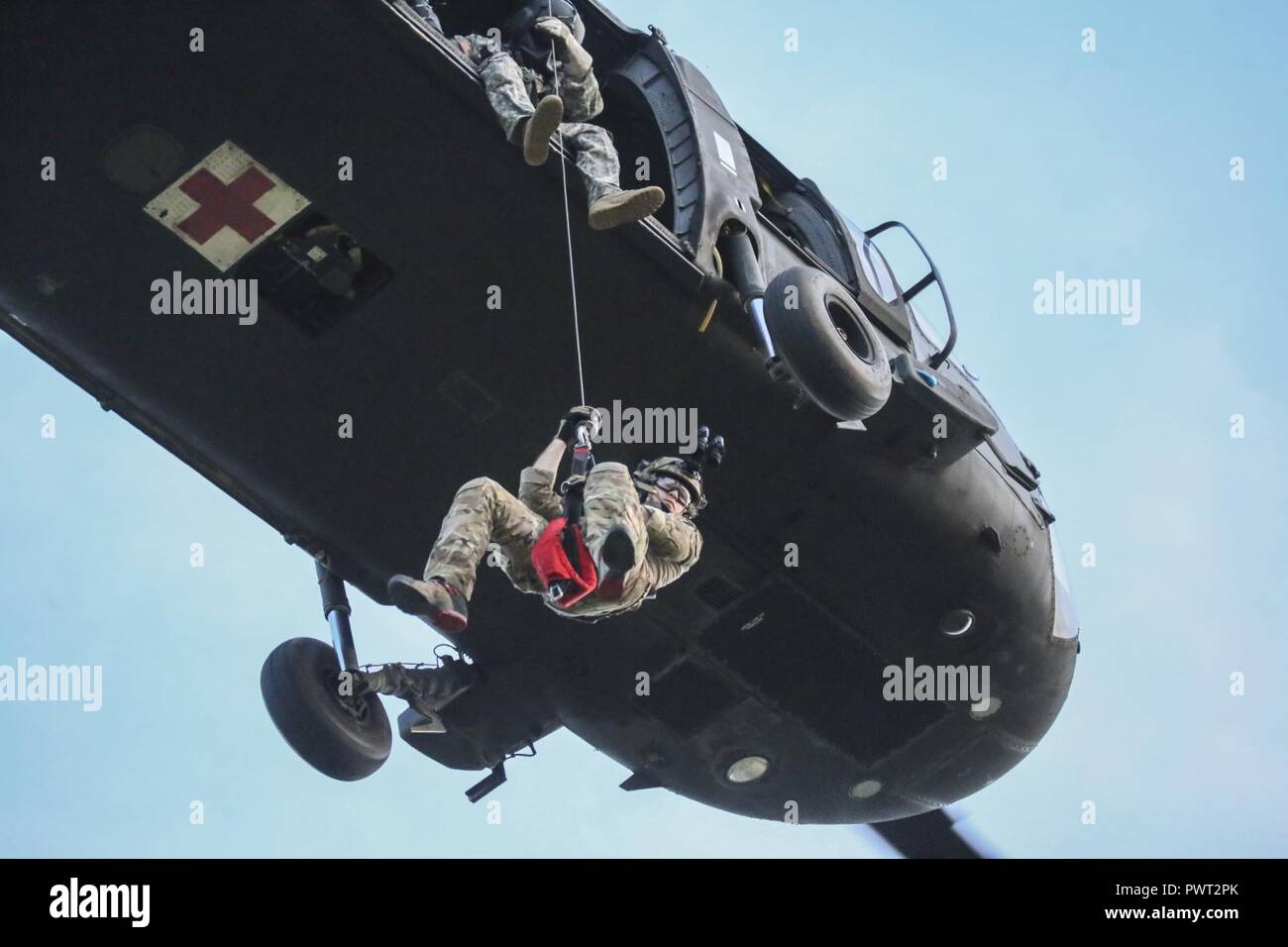 U.S. Air National Guard Senior Airman Michael Curley descends from a UH-60 Black Hawk helicopter during joint training for New Jersey Task Force One at Joint Base McGuire-Dix-Lakehurst, N.J., June 28, 2017. The primary mission of New Jersey Task Force One is to provide advanced technical search and rescue capabilities to victims trapped or entombed in structurally collapsed buildings. Task Force One is made up of New Jersey National Guard Soldiers and Airmen, as well as civilians. Stock Photo