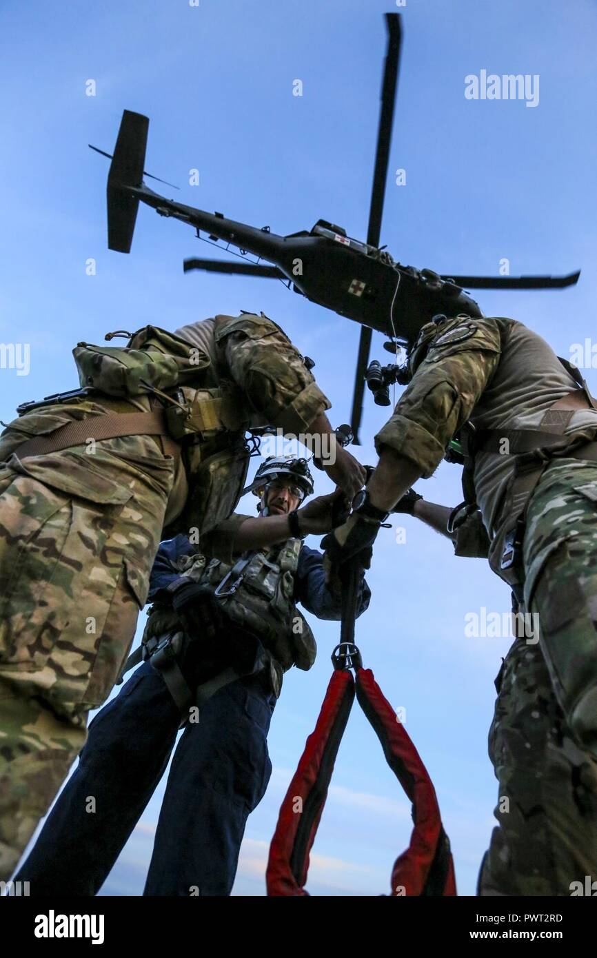 Members of New Jersey Task Force One are briefed on the hoist system on a UH-60 Black Hawk helicopter during joint training at Joint Base McGuire-Dix-Lakehurst, N.J., June 28, 2017. The primary mission of New Jersey Task Force One is to provide advanced technical search and rescue capabilities to victims trapped or entombed in structurally collapsed buildings. Task Force One is made up of New Jersey National Guard Soldiers and Airmen, as well as civilians. Stock Photo