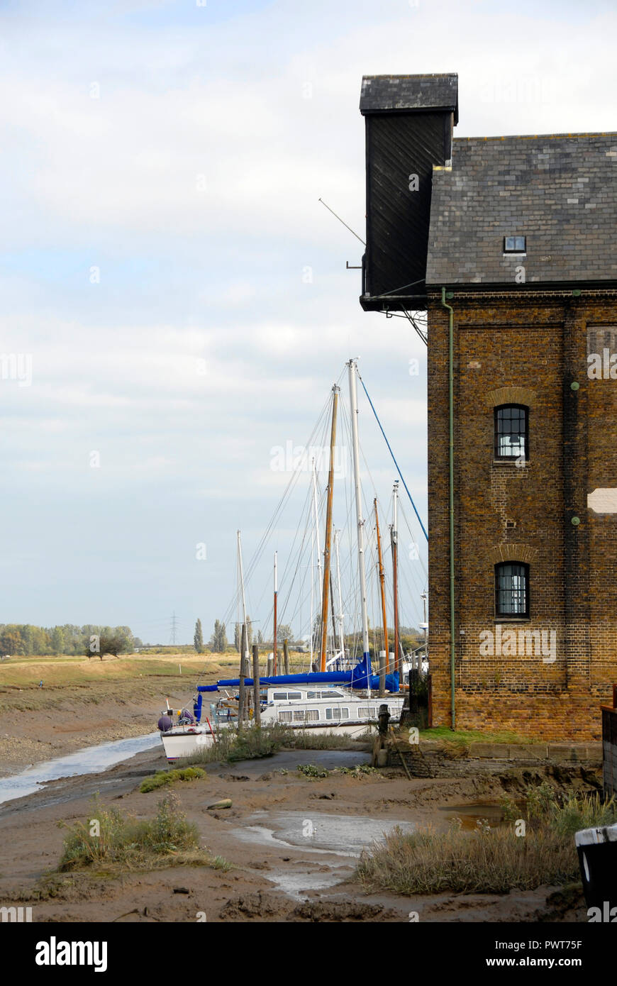 Boats aground at low tide beside former warehouse, Faversham, Kent, England Stock Photo