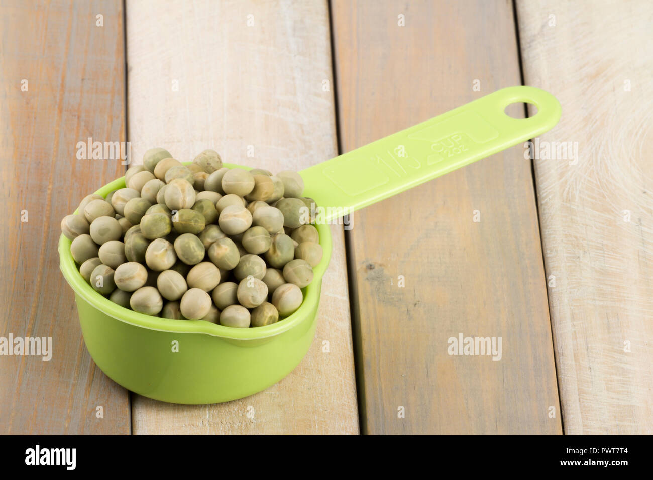 measuring cup with dried peas on wooden background Stock Photo
