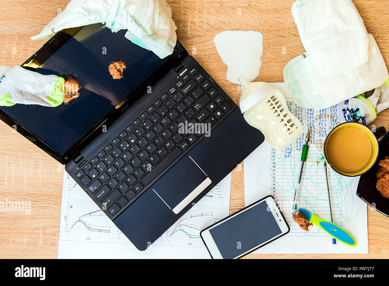 A concept image for having baby and working from home. Messy workplace,  diaper, porridge for a child on screen, spilled milk Stock Photo - Alamy