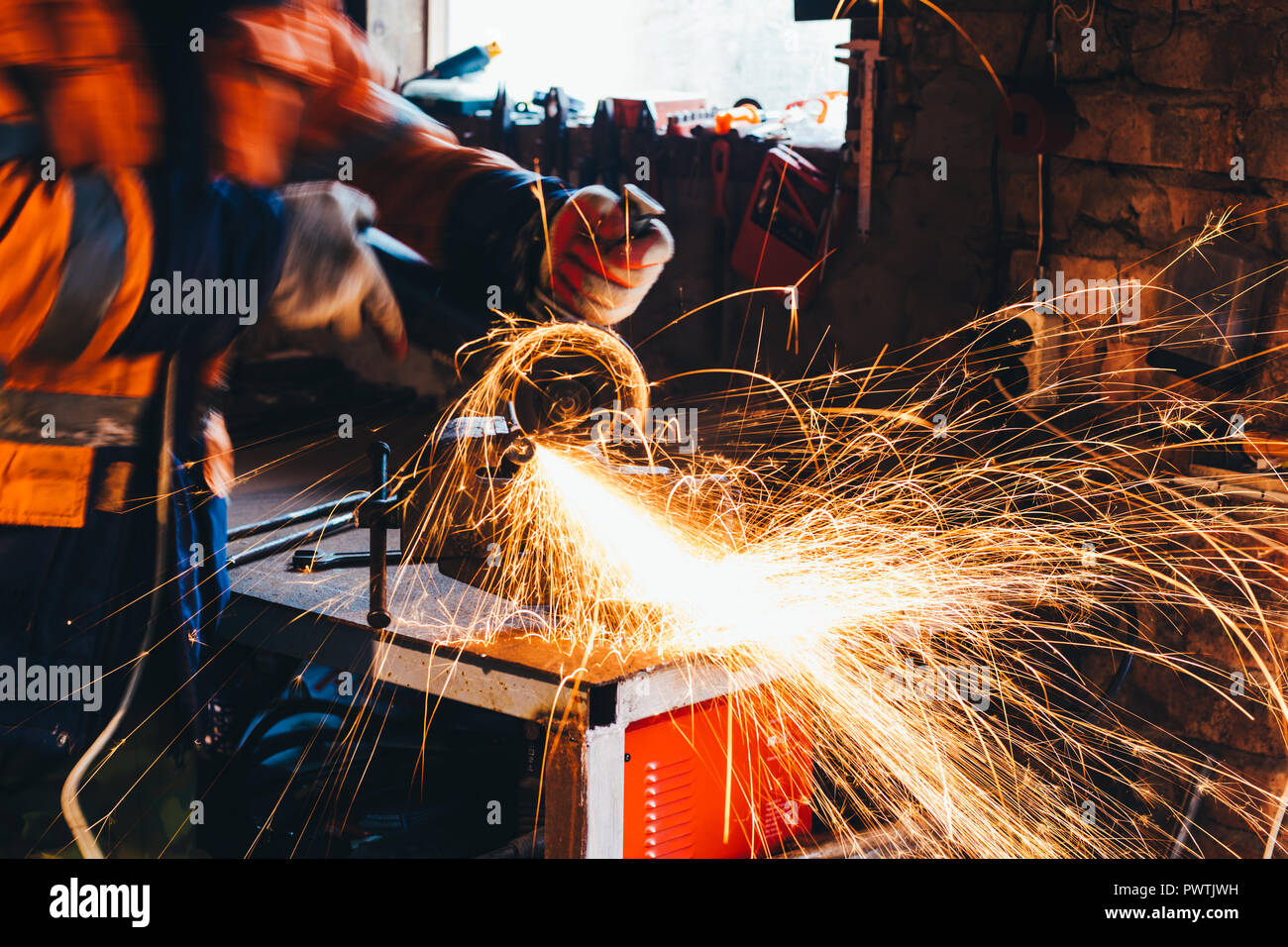 Worker cutting metal with grinder in his workshop. Sparks while grinding iron. Stock Photo