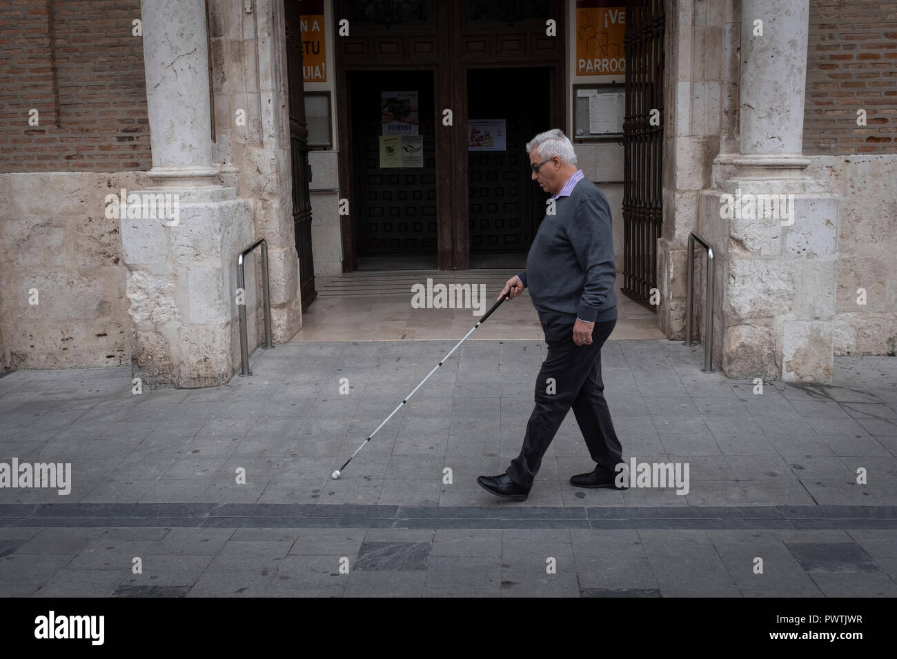 Blind man with cane walking alone on the street Stock Photo - Alamy