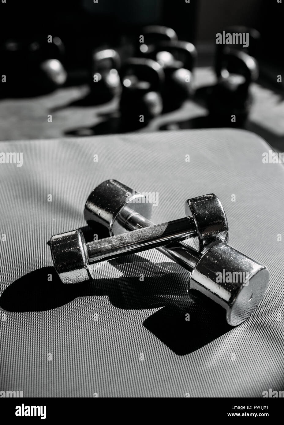 Chrome-plated dumbbells lying on a rubber floor in gym. Stock Photo