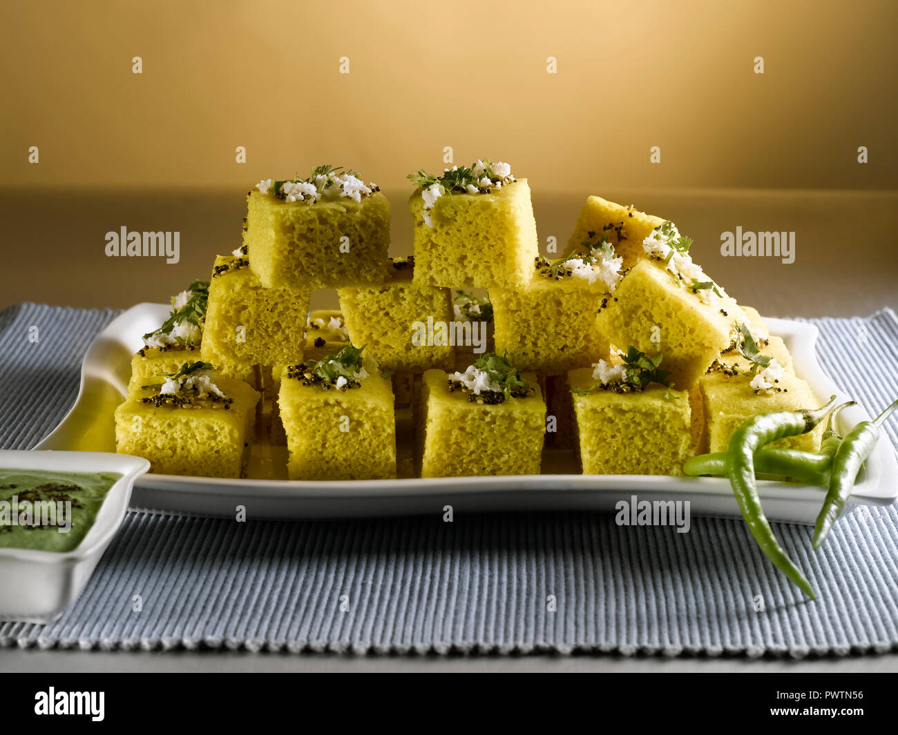 KHAMAN DHOKLA WITH CORIANDER CHUTNEY AND GREEN CHILLIES/ A STEAMED PASTRY MADE FROM GRAM FLOUR