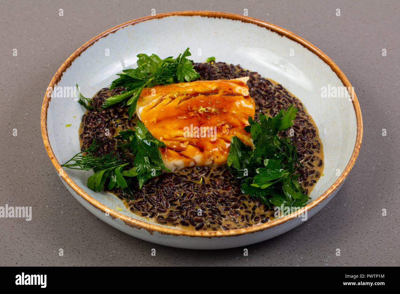 Cod fish with black rice Stock Photo - Alamy