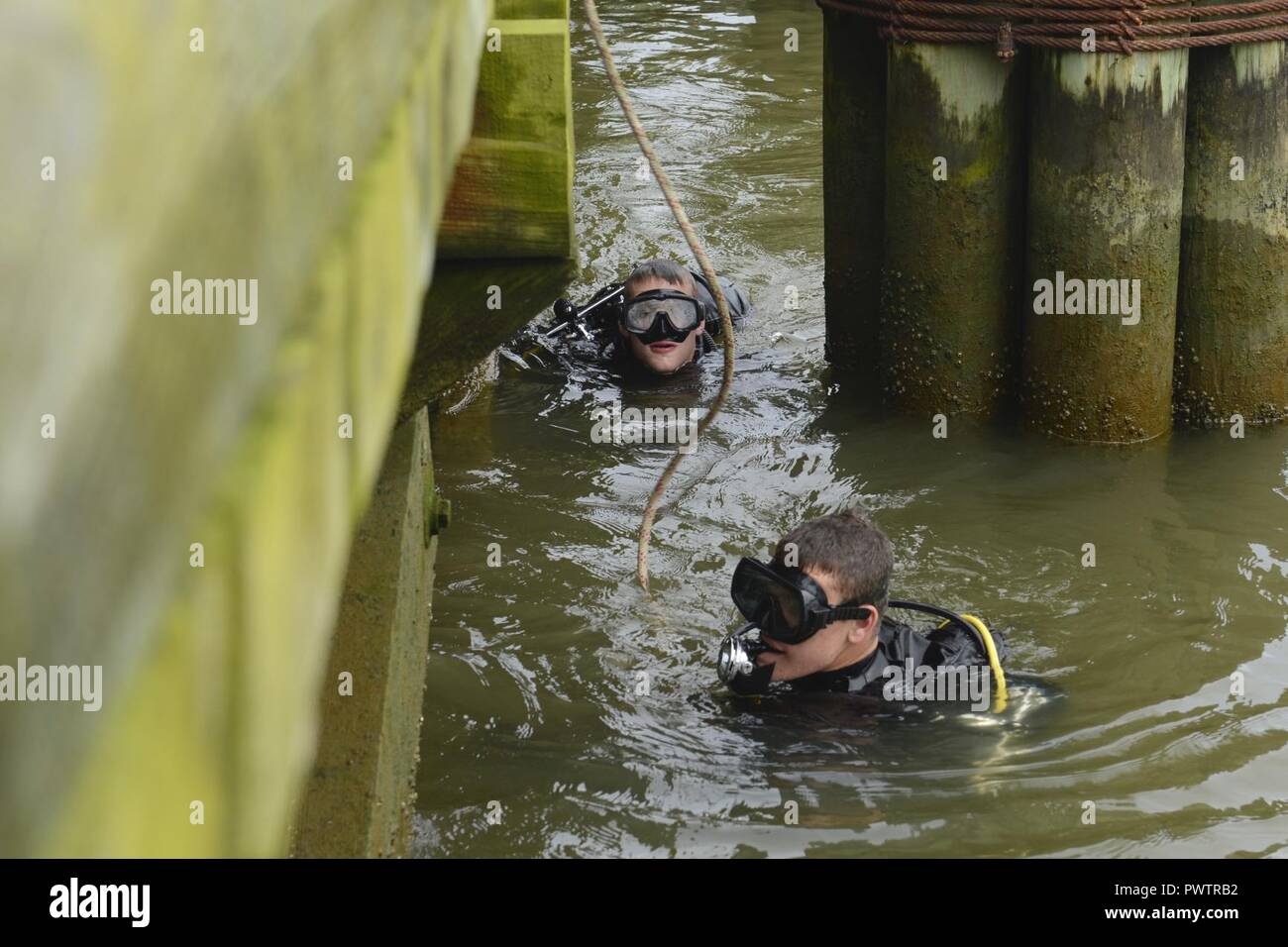 U.S. Army Pfc. Kyle Grimes, front, and Pfc. Samuel Ladd, 74th Engineer Dive Detachment, 92nd Eng. Battalion second class divers, inspect Third Port’s piers during a diving mission at Joint Base Langley-Eustis, Va., June 20, 2017. The detachment uses inspection assignments to train younger divers and help them improve their techniques. Stock Photo