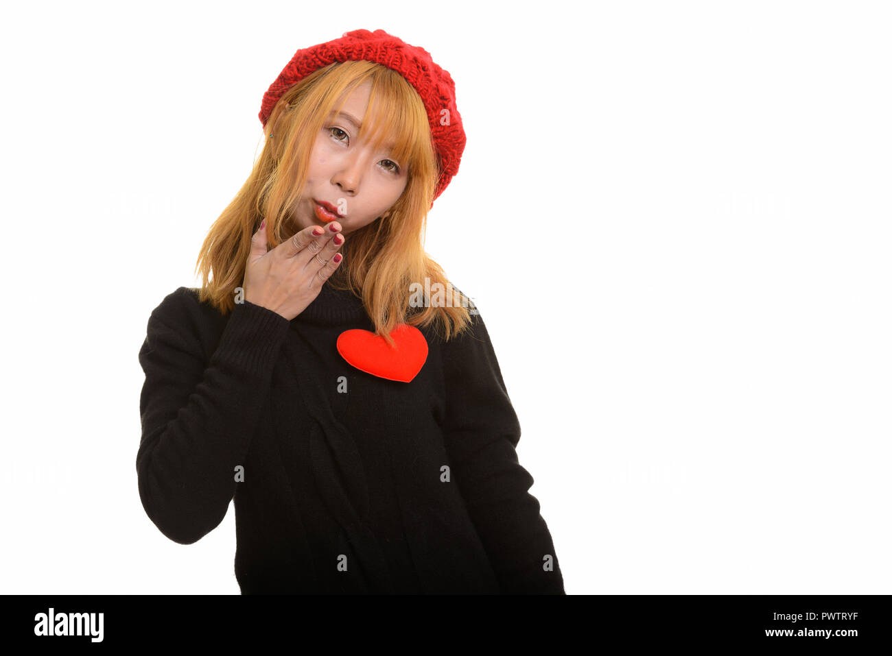 Young cute Asian woman with red heart on chest and blowing kiss Stock Photo