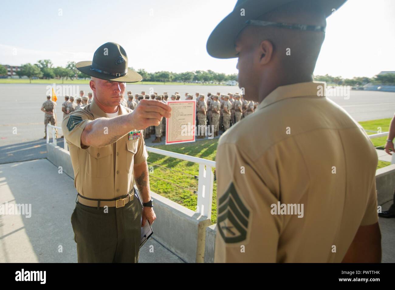 U.S. Marine Corps Staff Sgt. Wesley Paulk, the 2nd Recruit Training Battalion drillmaster, hands a list of commands to a drill instructor before an initial drill evaluation June 19, 2017, on Parris Island, S.C. Drillmasters, like Paulk, 31, from Baton Rouge, La., are experts on the Marine Corps Drill and Ceremonies Manual and grade each platoon and its drill instructor on their ability to perform close-order drill movements. Alpha Company is scheduled to graduate Aug. 11, 2017. Parris Island has been the site of Marine Corps recruit training since Nov. 1, 1915. Today, approximately 19,000 recr Stock Photo
