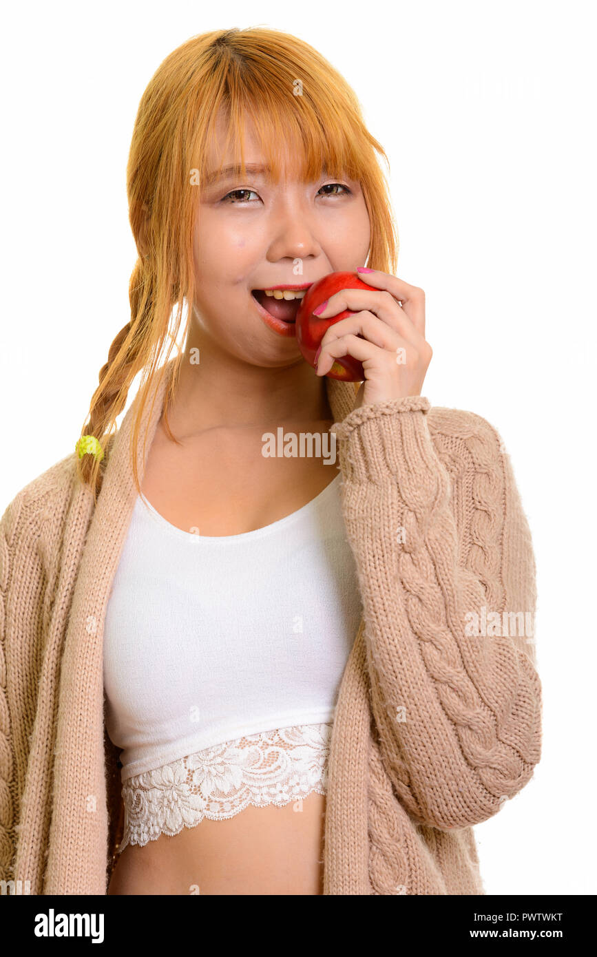 Young happy Asian woman smiling and eating red apple  Stock Photo