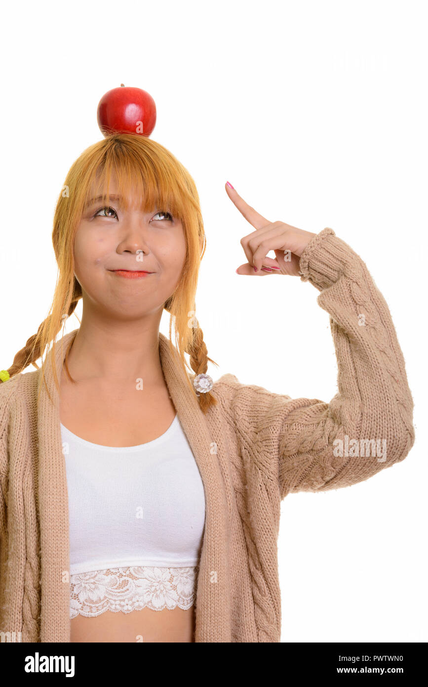 Young cute Asian woman with apple on head and pointing finger Stock Photo