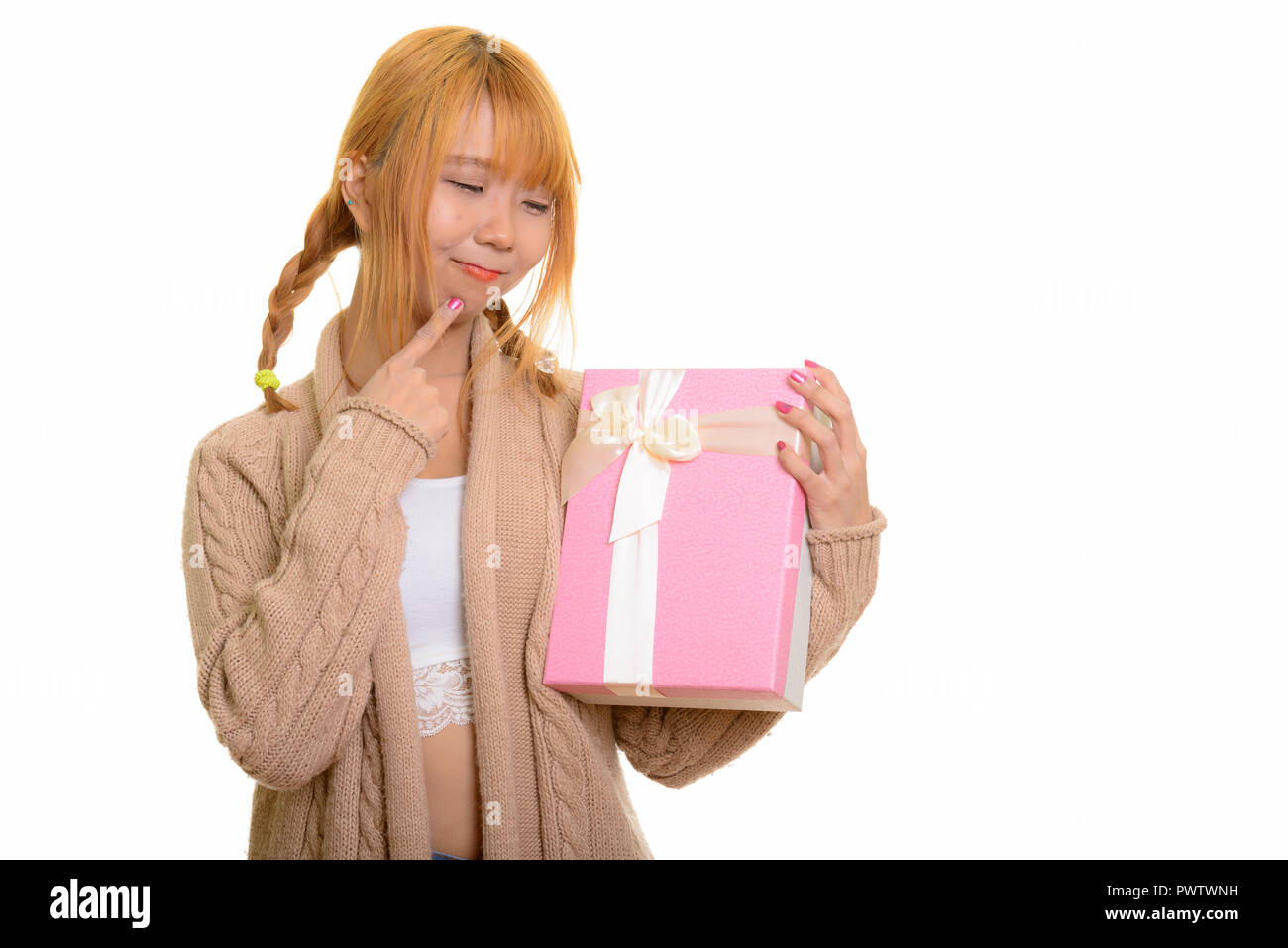Young cute Asian woman holding gift box while thinking Stock Photo