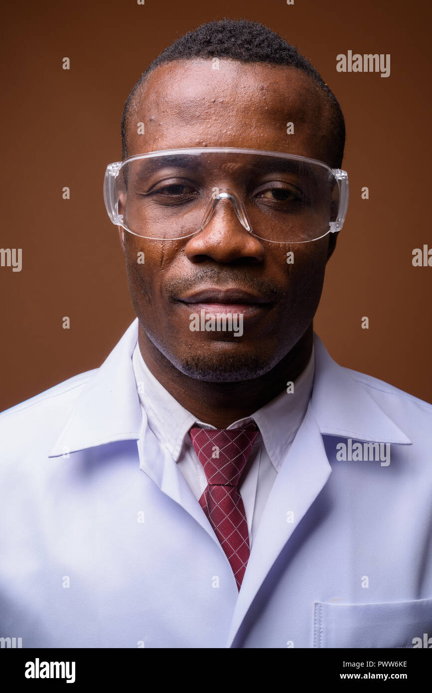 Studio shot of young African man doctor against brown background Stock Photo