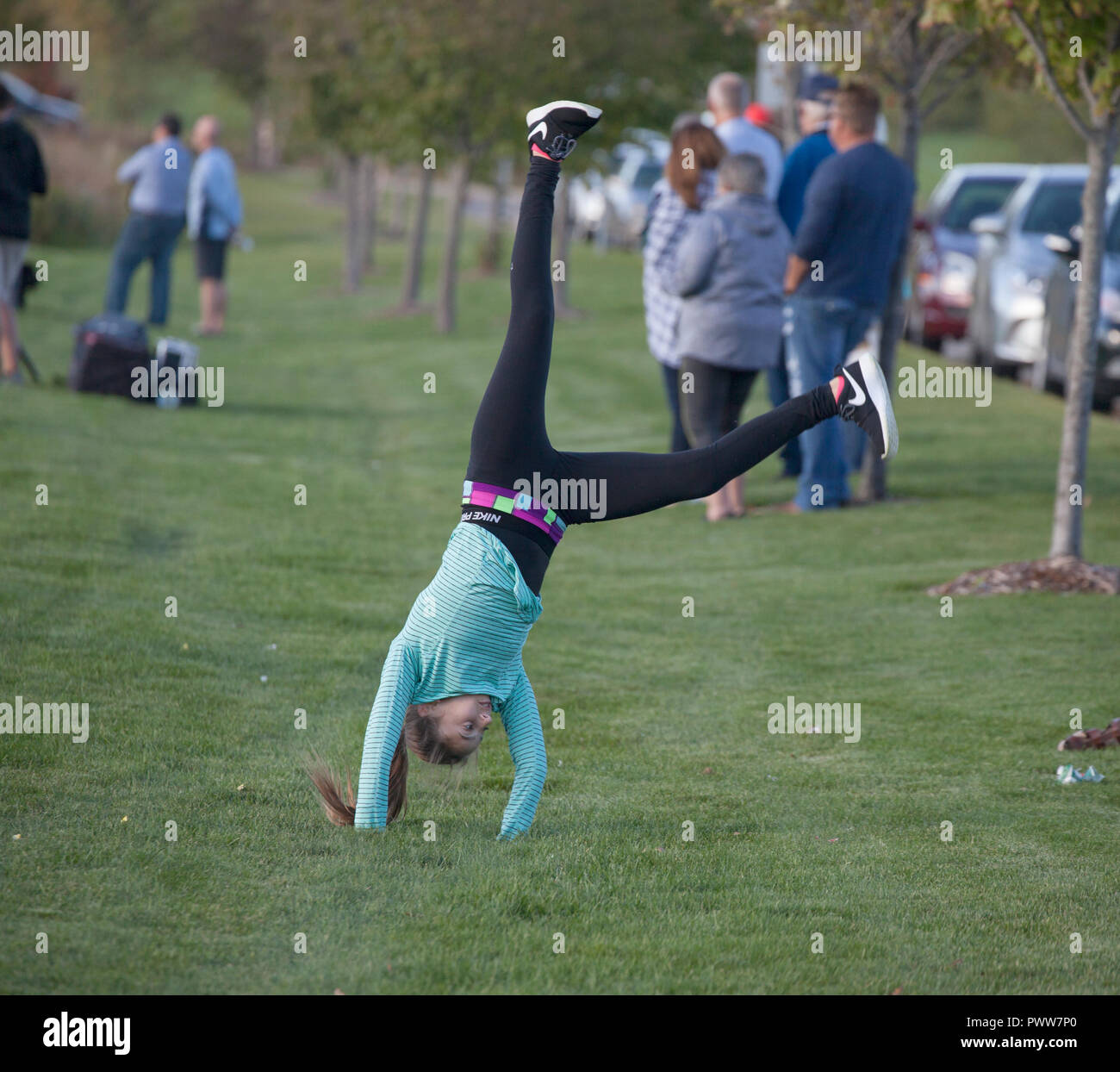 Free spirited young girl age 11, bored with watching a neighborhood football game, does cartwheels for her pleasure. Mendota Heights Minnesota MN USA Stock Photo