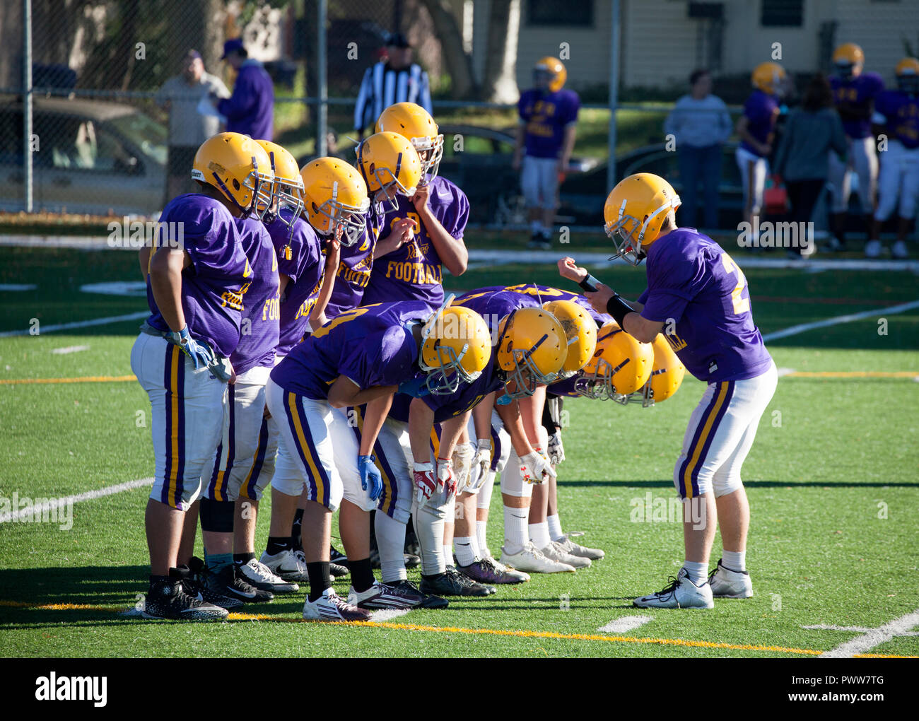 Quarterback reads the game play from wrist for Cretin-Durham Hall High School football team in the huddle on the field. St Paul Minnesota MN USA Stock Photo
