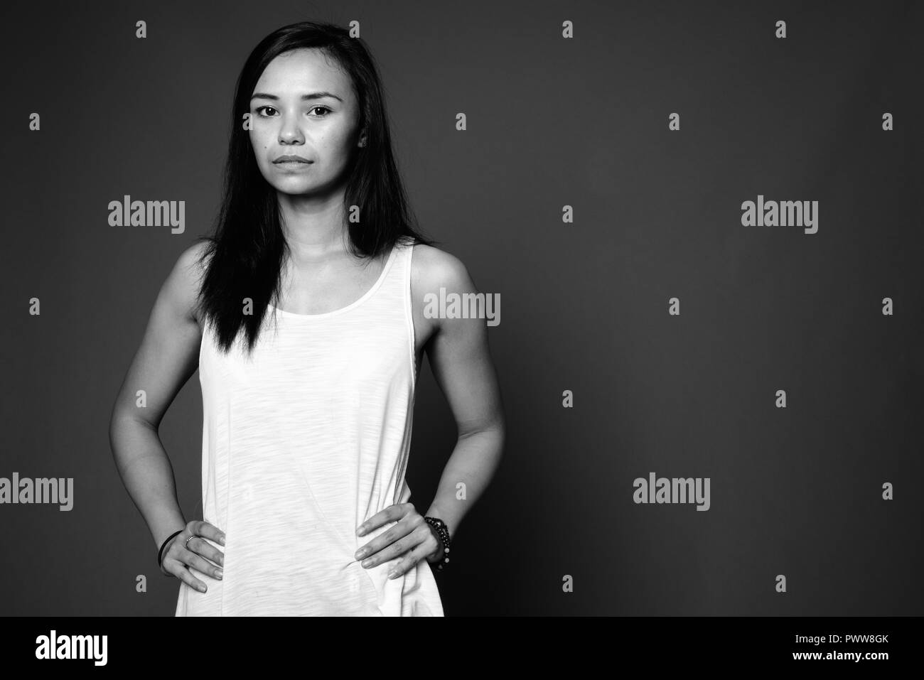 Young Asian woman against gray background in black and white Stock Photo