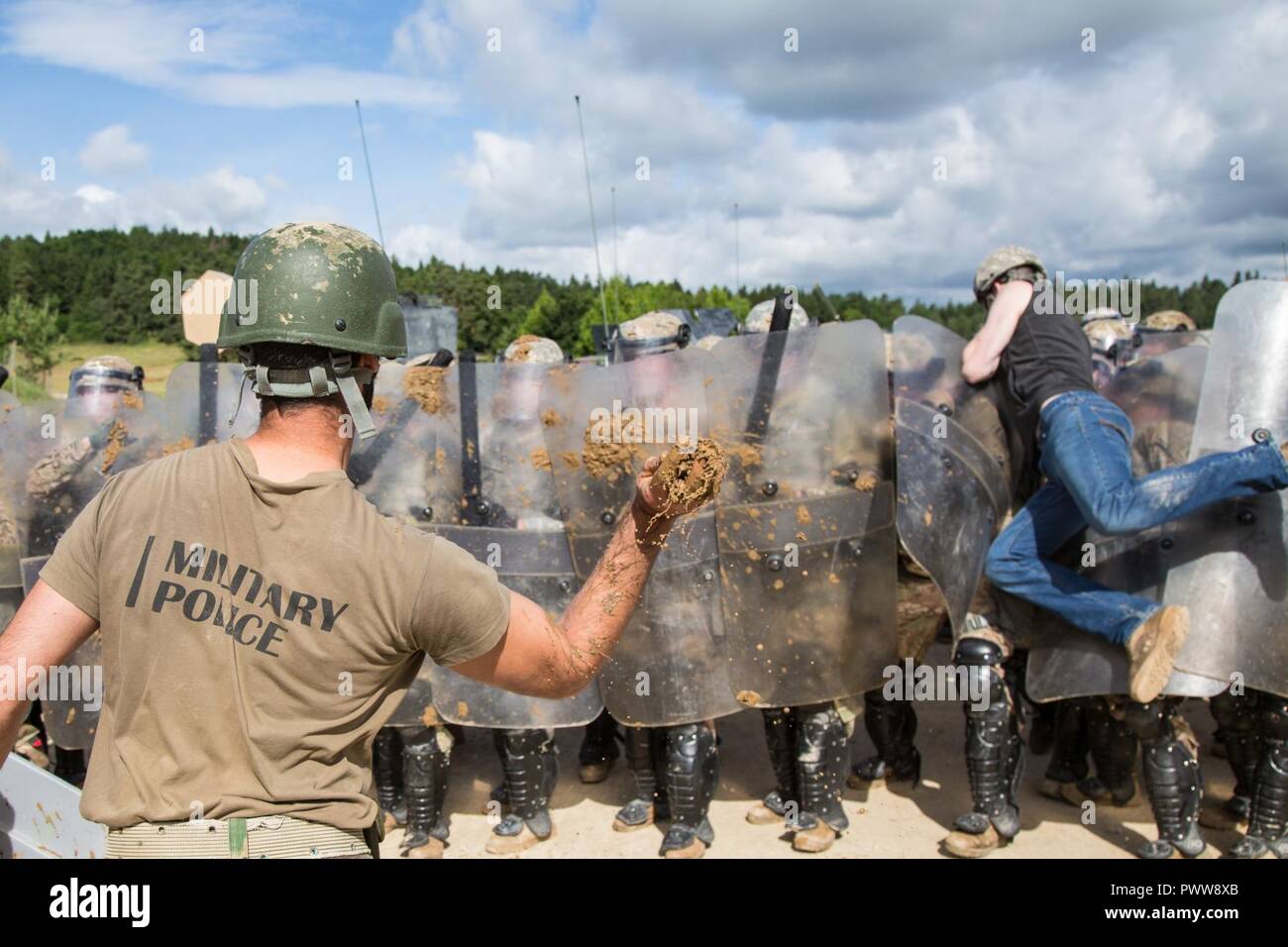 A Portuguese soldier, left, of the 2nd Lancers Regiment throws mud while conducting a crowd riot control scenario during a Kosovo Force (KFOR) mission rehearsal exercise (MRE) at the Joint Multinational Readiness Center in Hohenfels, Germany, June 30, 2017. The KFOR MRE 23 is designed to prepare the 39th Infantry Brigade Combat Team for their deployment to Kosovo in support of civil authorities to maintain a safe and secure environment. KFOR MRE 23 hosts 900 soldiers from 10 nations. The exercise runs from June 19 through July 11 in Hohenfels, Germany. Stock Photo