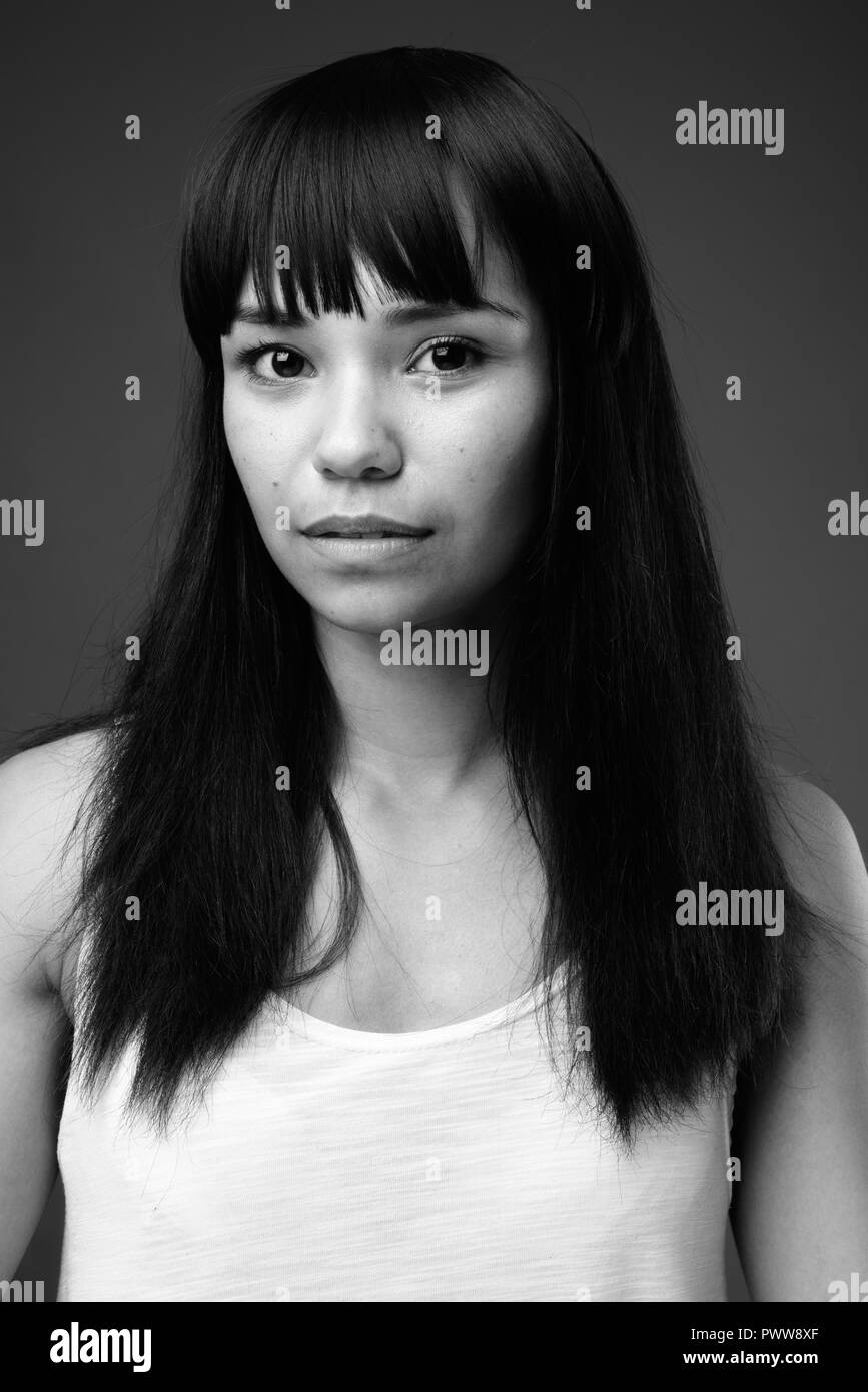 Young Asian woman against gray background in black and white Stock Photo