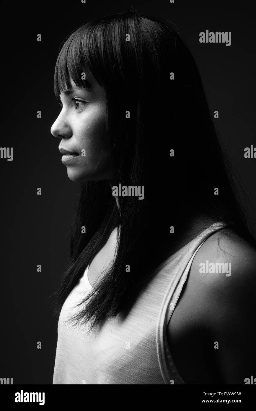 Young Asian woman against gray background in black and white Stock Photo
