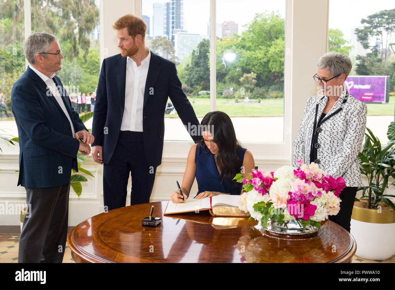 The Duke and Duchess of Sussex sign the visitor book at Government House, alongside Governor of Victoria Linda Dessau (right) and her husband Anthony Howard (left) at a reception given by the Governor of Victoria, at Government House during their visit to Melbourne, on the third day of the royal couple's visit to Australia. Stock Photo