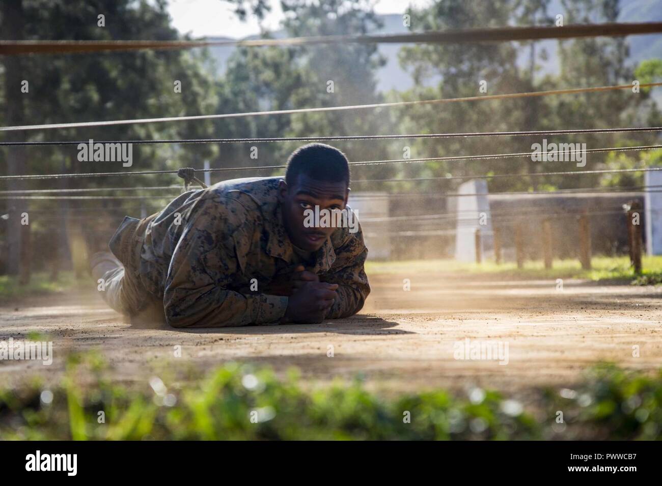U.S. Marine Corps Lance Cpl. Tyreke Wiggins, an infantryman with Task Force Koa Moana 17, low crawls under an obstacle as a part of the North Atlantic Treaty Organization  obstacle course at Plum, New Caledonia, June 30, 2017. Koa Moana 17 is designed to improve interoperability with our partners, enhance military-to-military relations, and expose the Marine Corps forces to different types of terrain for familiarity in the event of a natural disaster in the region. Stock Photo