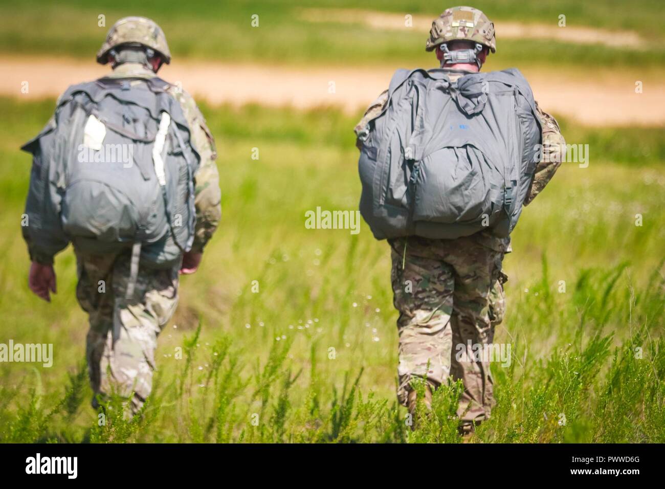 Two Soldiers assigned to 2nd Battalion, 505th Parachute Regiment, 3rd Brigade Combat Team walks to the flight landing strip after jumping from a CH-47 Chinook helicopter assigned to 3rd General Support Aviation Battalion, 82nd Combat Aviation Brigade during airborne operations on Sicily Drop Zone at Fort Bragg, N.C., July 6, 2017. Stock Photo