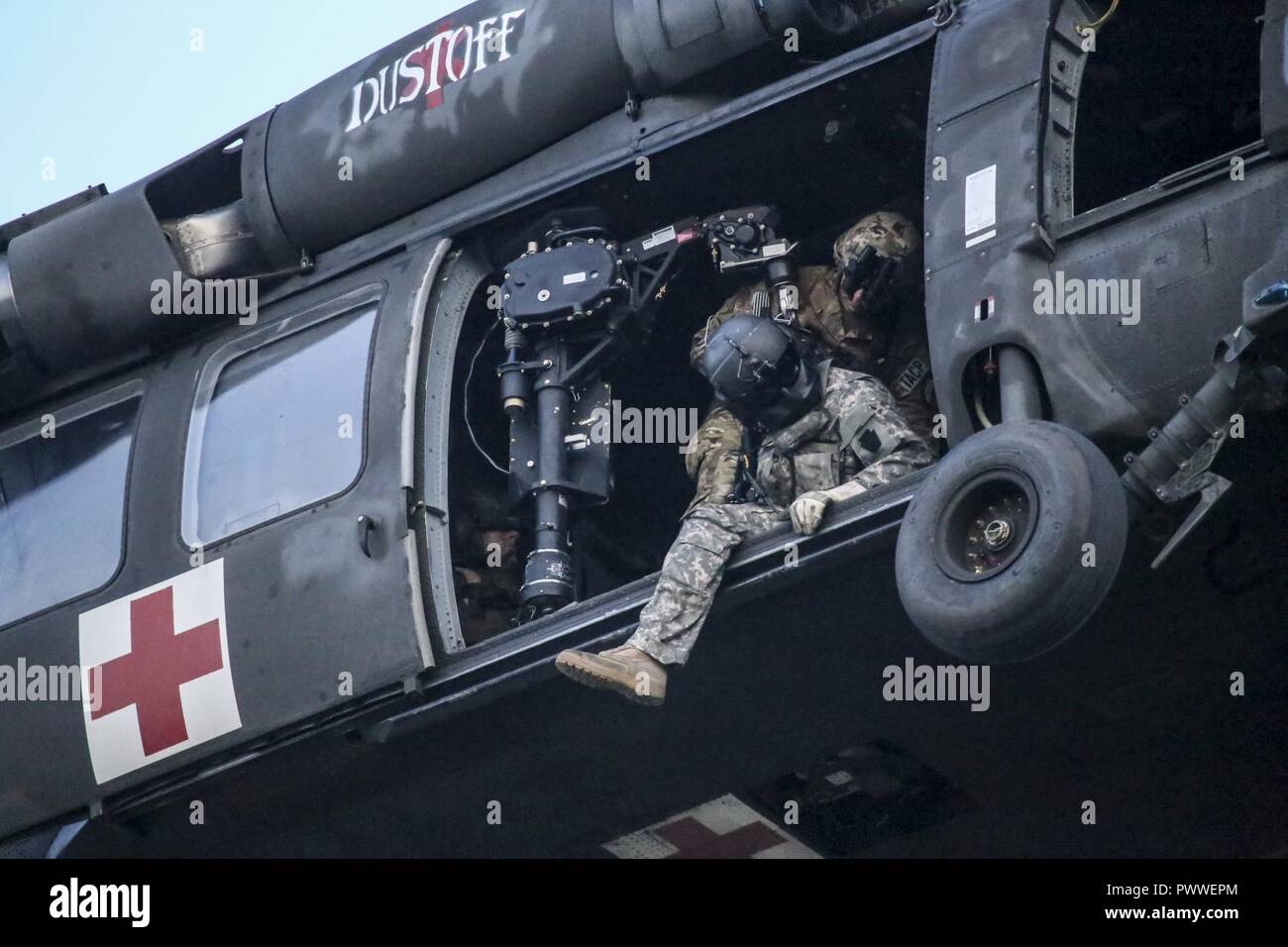 U.S. Army National Guard Sgt. Timothy Witts, a UH-60 Black Hawk helicopter crew chief, scans the area before lowering a hoist during joint training for New Jersey Task Force One at Joint Base McGuire-Dix-Lakehurst, N.J., June 28, 2017. The primary mission of New Jersey Task Force One is to provide advanced technical search and rescue capabilities to victims trapped or entombed in structurally collapsed buildings. Stock Photo