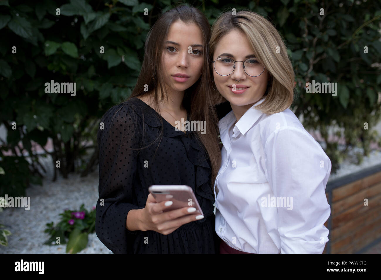 Two young women are standing on the street and using a smartphone Stock ...