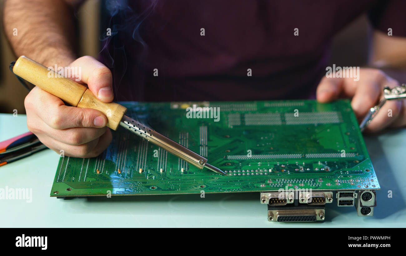Repair motherboard. A man soldering solder the contacts from the