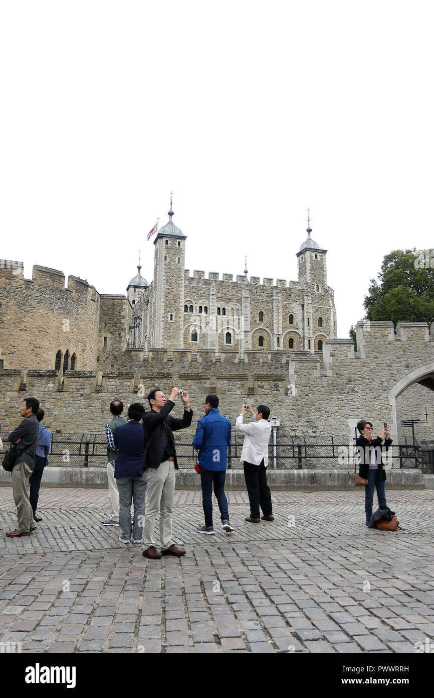 Tourists taking photographs and selfies outside the Tower of London, a historic London landmark and tourist attraction, London, UK. Stock Photo