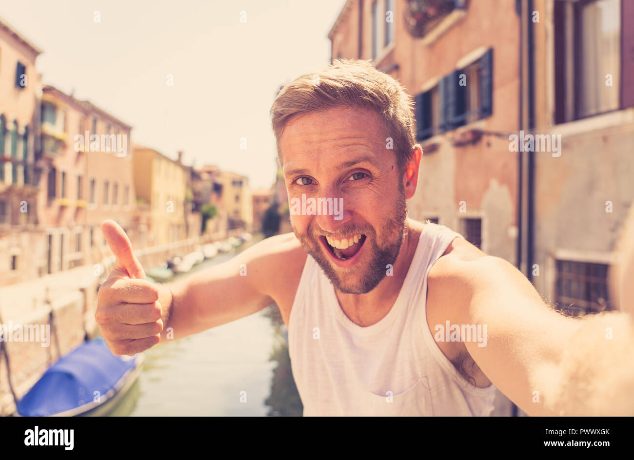 Young attractive t Caucasian blonde tourist taking selfie at venice canal having fun on vacation in Italy in Europe summer travel holiday concept. Stock Photo