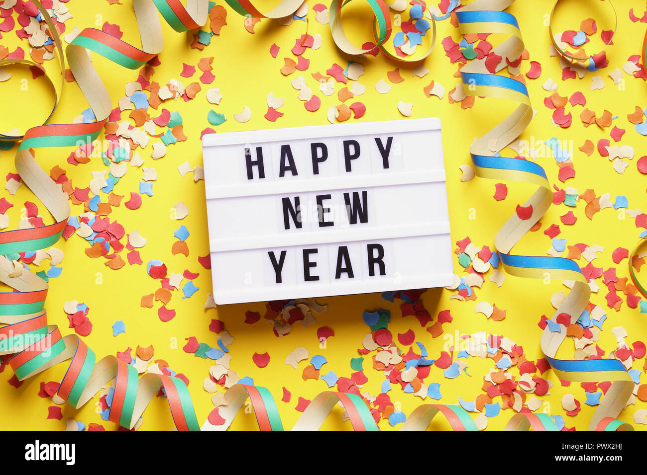 happy new year party celebration flat lay with confetti and streamers on yellow background Stock Photo