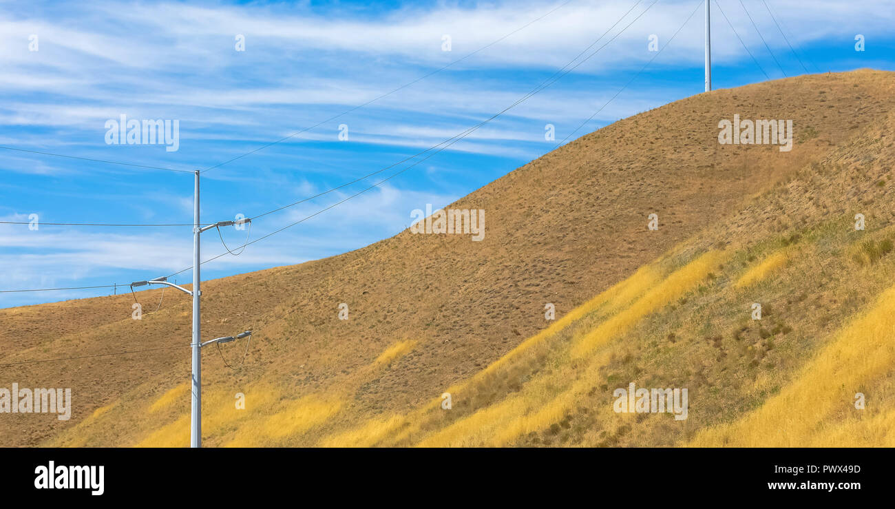 Power lines on a hill under a cloudy blue sky Stock Photo - Alamy