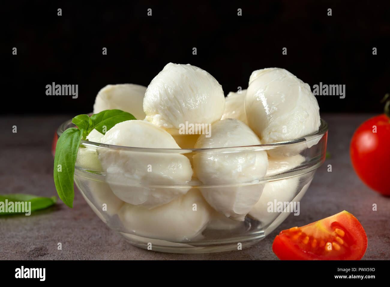 Glass bowl with mozzarella cheese balls, cherry tomato and basil Stock Photo