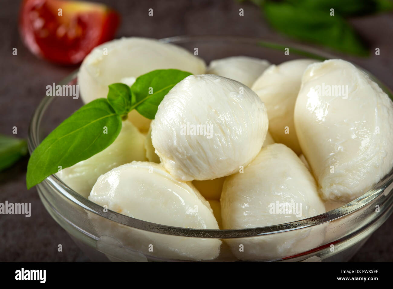 Glass bowl with mozzarella cheese balls, cherry tomato and basil - close up view Stock Photo