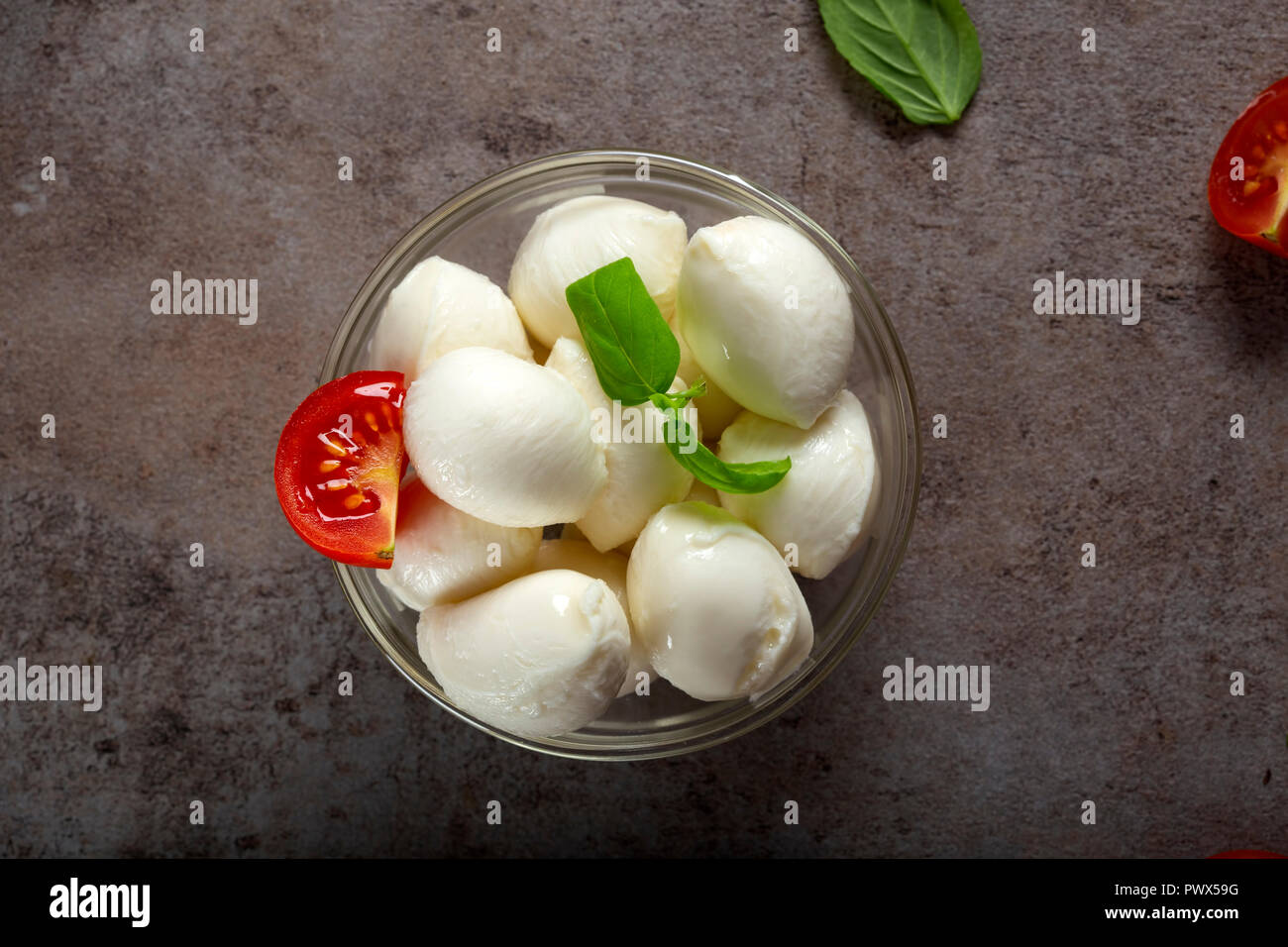 Glass bowl with mozzarella cheese balls, cherry tomato and basil - top view Stock Photo