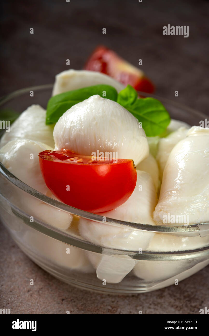 Glass bowl with mozzarella cheese balls, cherry tomato and basil - close up view Stock Photo