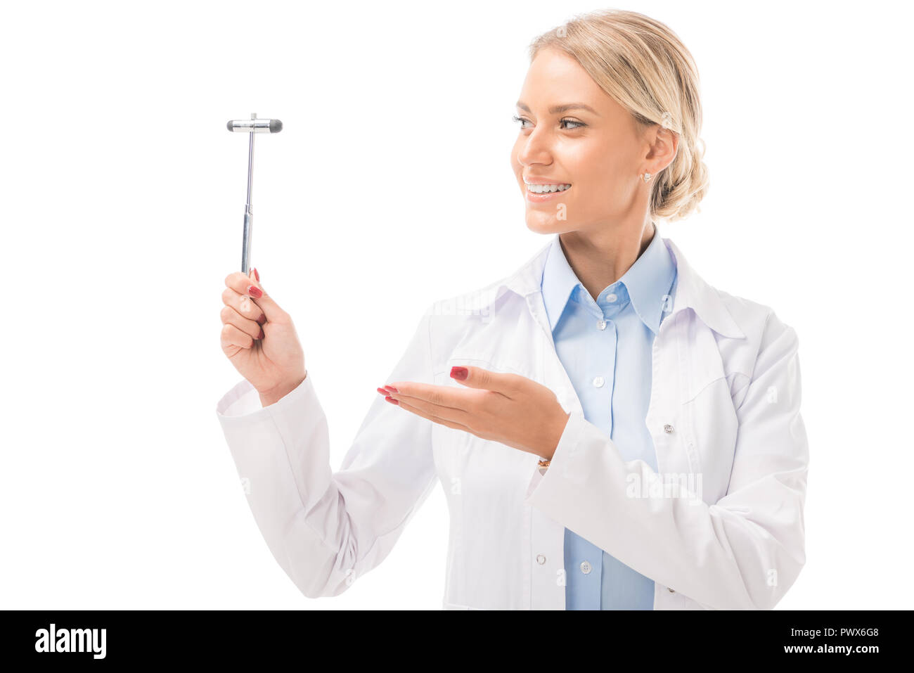 smiling young female neurologist pointing at reflex hammer isolated on white Stock Photo