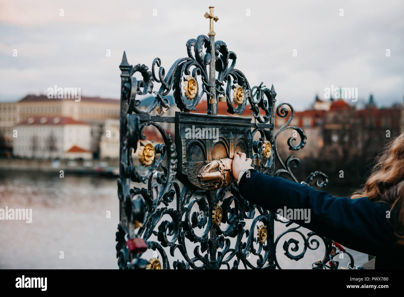 A female tourist touches a bronze statue of John of Nepomuk on