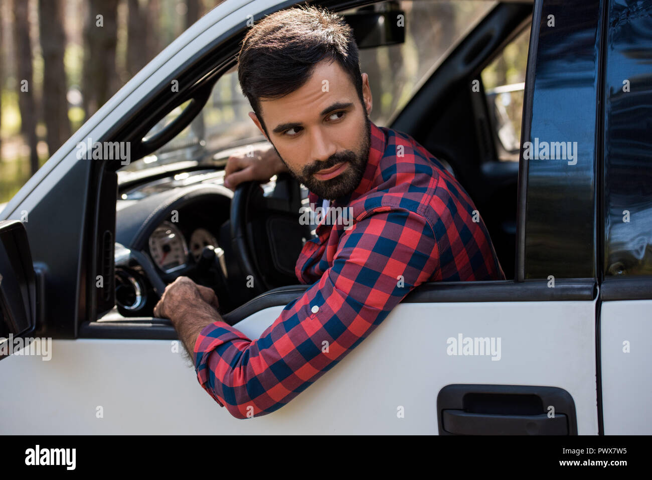 bearded driver holding steering wheel in pickup truck in forest Stock ...