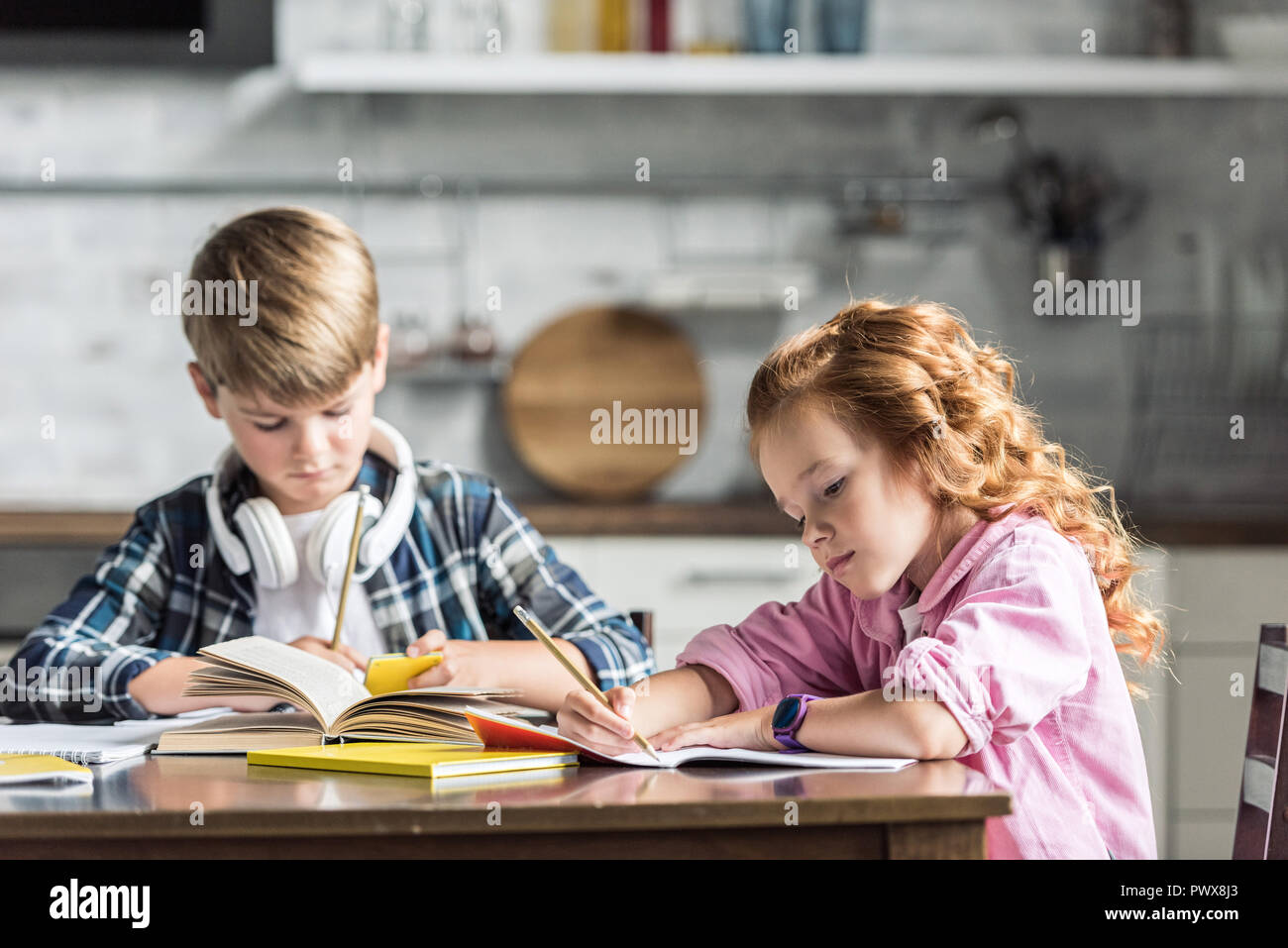 concentrated little kids doing homework together at kitchen Stock Photo ...