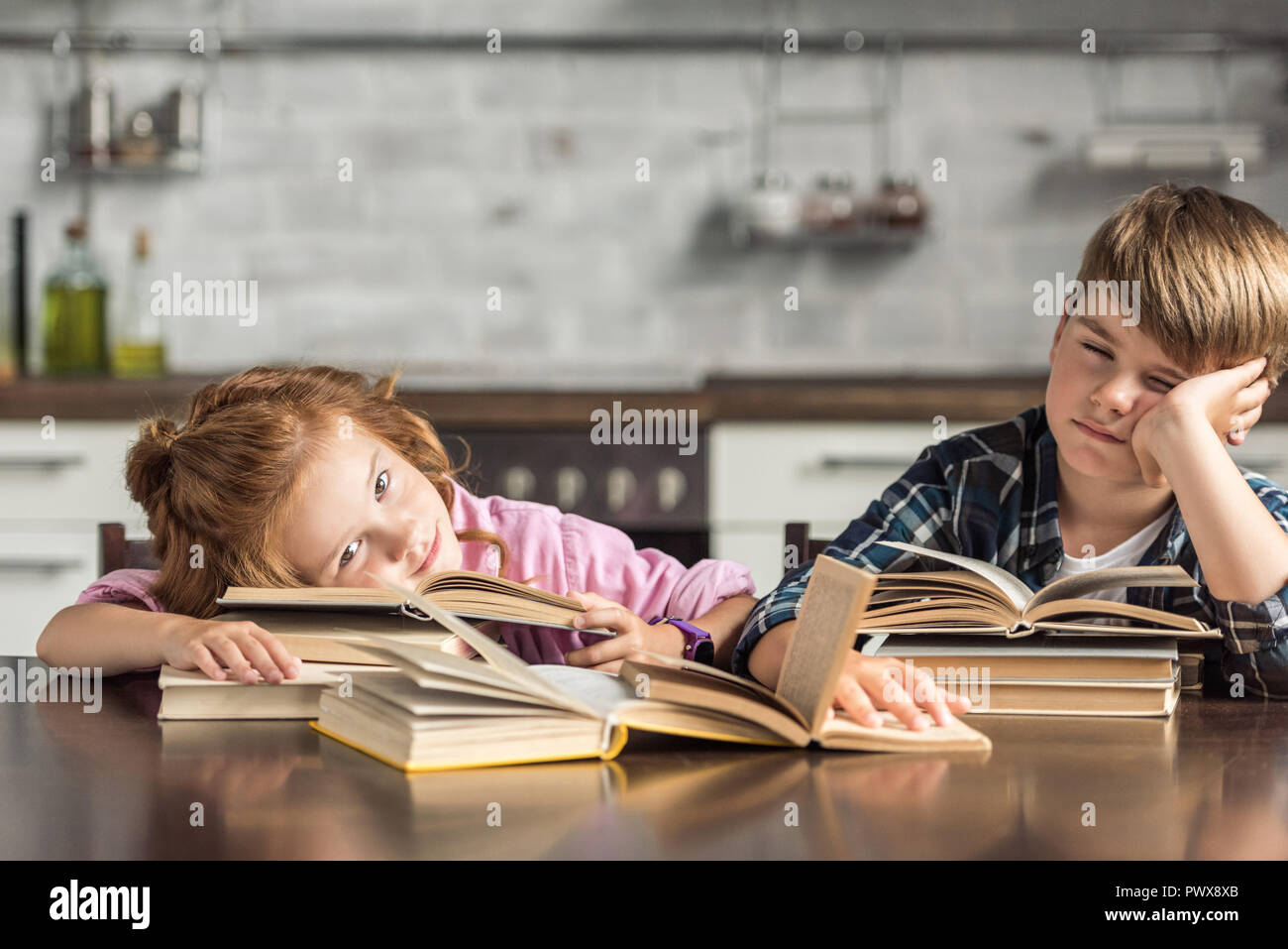 tired little scholars sleeping on book while doing homework Stock Photo