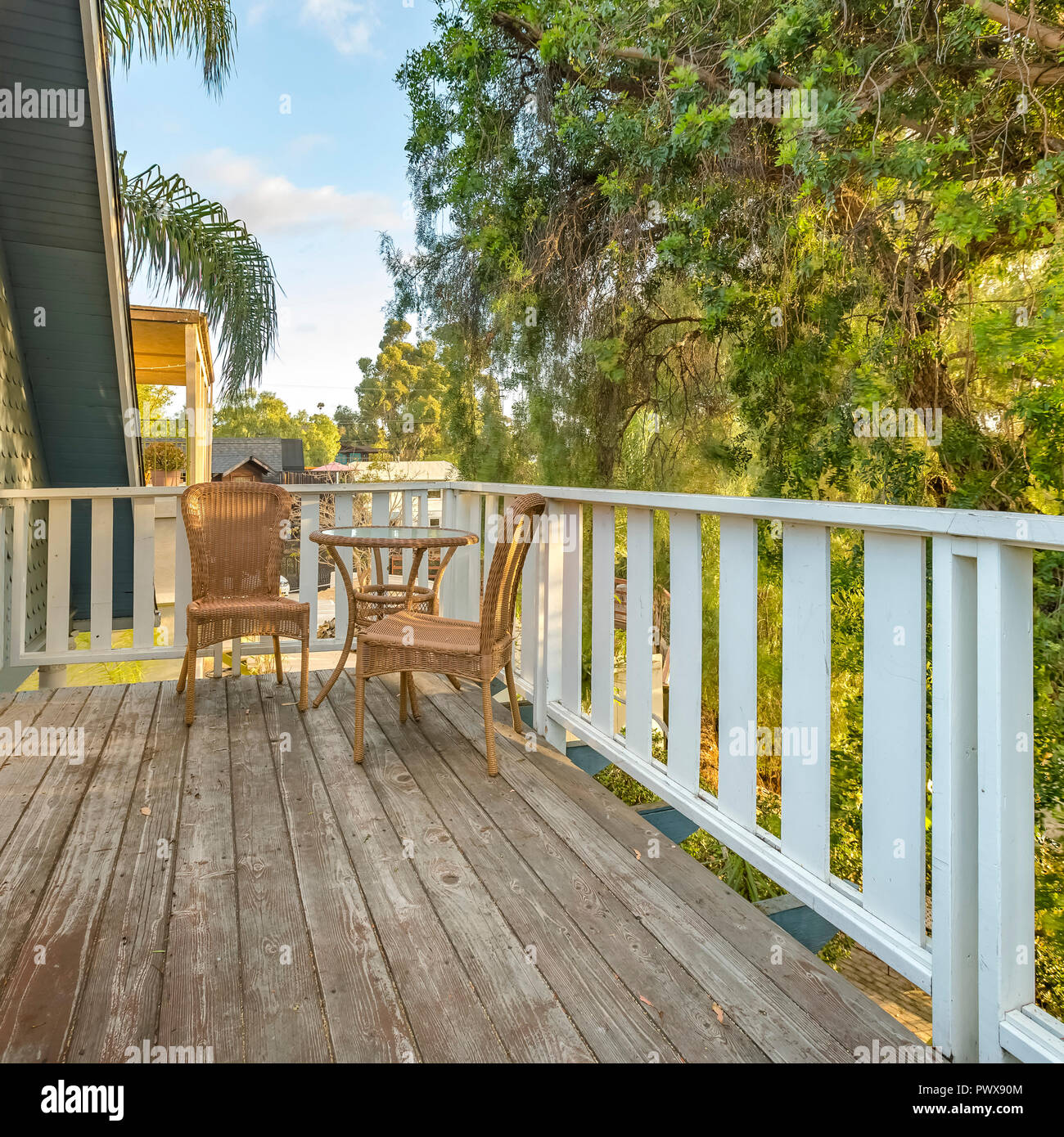Wicker chairs and table on a balcony beside trees Stock Photo - Alamy
