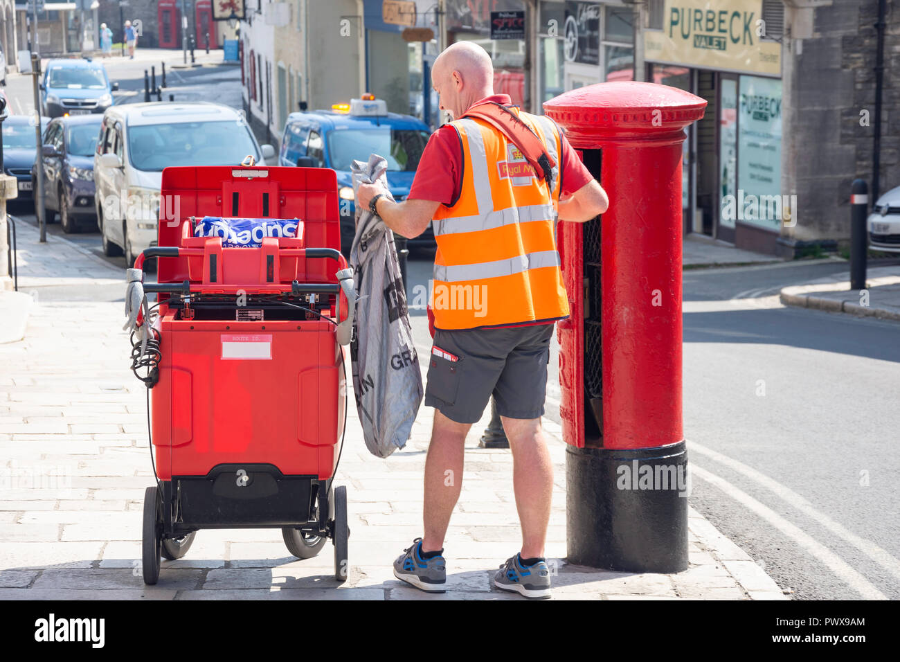 Royal Mail postman emptying a post box, High Street, Swanage, Isle of Purbeck, Dorset, England, United Kingdom Stock Photo