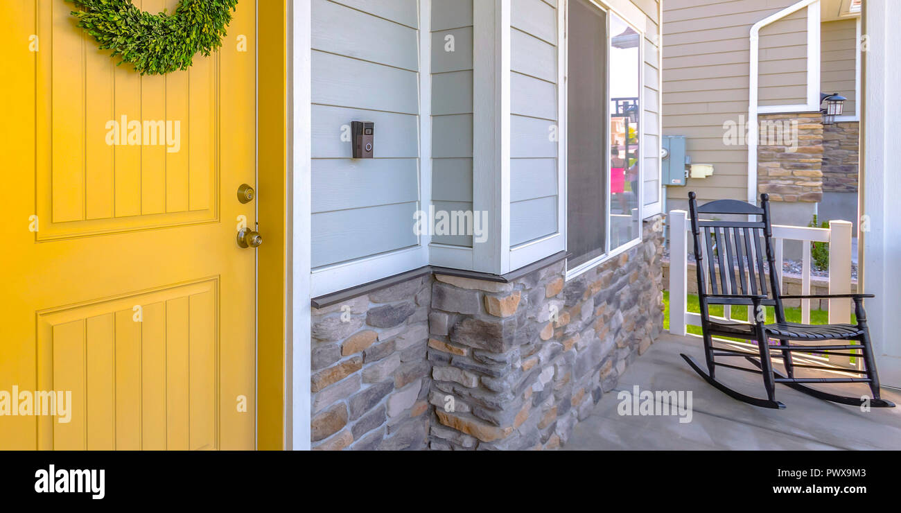 Yellow front door and porch with a rocking chair Stock Photo