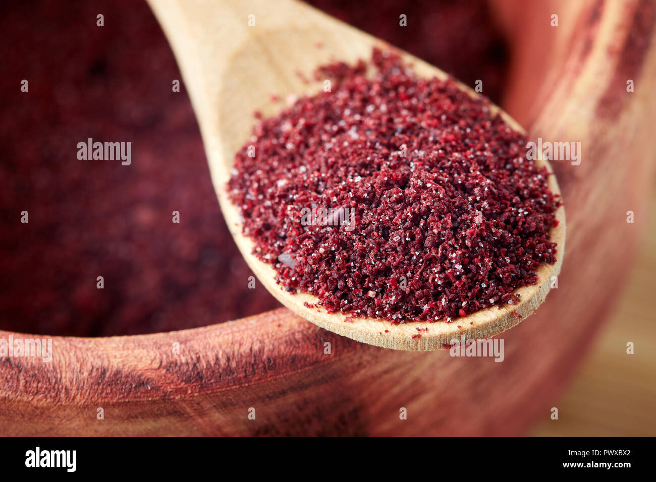 Close up of ground sumac spice powder in wooden spoon Stock Photo